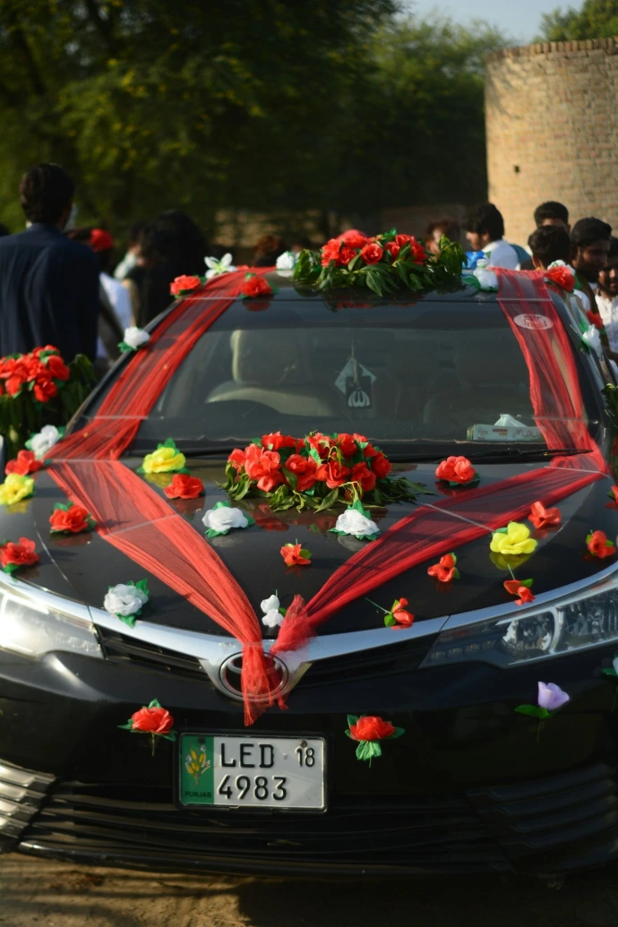 Black car decorated with red and white flowers